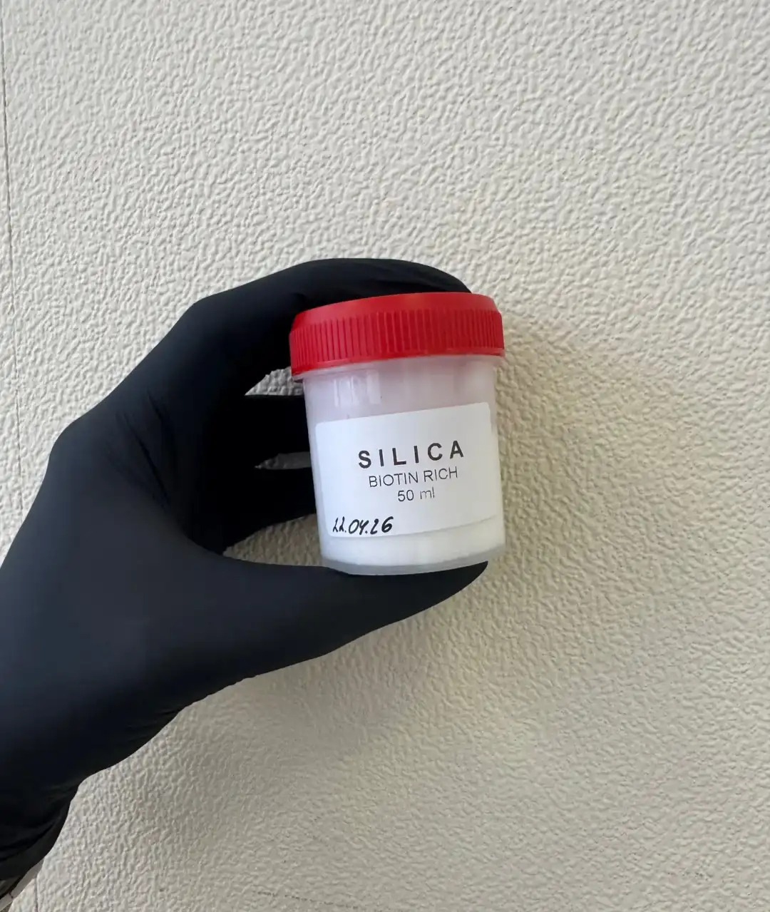 Баночка с образцом SILICA в руке в чёрной перчатке